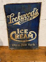 Front side of the antique Lockwood's Ice Cream metal sign showing blue background with white script text.