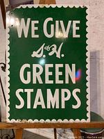 Front side full view on stand, green enamel background with white scalloped border and bold text