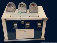 Front view showing three stamp dispensers labeled with different postage values and the AMERICAN POSTMASTER label with a dome building.