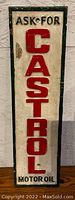 Front view of heavy iron Castrol motor oil sign, showing red raised letters and painted text on white and green background.