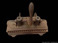 Top view of the cast iron cigar press showing handle and ribbed mold area.