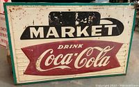 Front view of metal marquee sign with “MARKET” and “Drink Coca-Cola” graphics