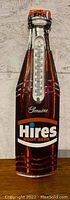 Front view of the metal sign shaped like a Hires Root Beer bottle with thermometer slot but no mercury element.