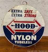 Front view of the round metal sign showing the 'Extra Safe... Extra Strong HOOD Nylon Tubeless' branding in red, white, and blue.