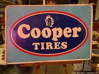 Photo showing the full Cooper Tires metal sign with the logo and colors clearly visible.