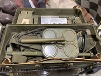 Open carrying case showing the contents of the mine detector kit, including metal detector heads with circular coils and cables.