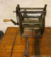 Front view of steel reel mounted on frame showing wooden crank handle and chain drive