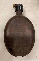 Full front view of the WWII German canteen showing oval shape, screw top cap, and patina on metal surface.