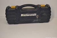 Closed blue plastic carrying case with handle and yellow latches stamped with 'Mastercraft'