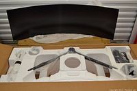 Monitor panel and stand components unboxed in foam packaging