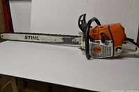 Full side view of Stihl chainsaw showing 36" bar, housing and handle on flat surface
