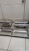 Two stainless steel chafing dishes with lids, two trays laid out in front