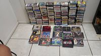 Wide view showing large stacks of vintage audio cassette tapes lined up with 50 assorted rock CDs in front spread on floor
