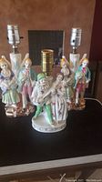 Three vintage porcelain lamps with Wales figurines on a table, showing overall condition and size