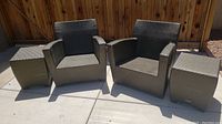 Two lounge chairs flanked by two cube side tables on concrete patio