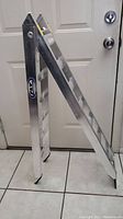 Side view of folded aluminum ramp leaning against door, showing Fly Racing logo sticker.