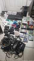 Overview of all consoles, controllers, games, and cables laid out on floor