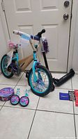 Dynacraft brand child's 3-wheel bike with protective cardboard wrapping and colorful seat, placed next to a black Jetson Orbit scooter with LED lights.