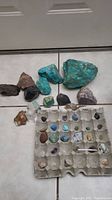 Overview of the rock collection showing rough and polished stones of various sizes and colors arranged on the floor with some organized in an egg carton.