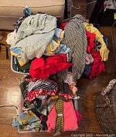 Bin and pile of assorted women's clothing showing mixed fabrics, colors, and patterns including red, black, beige, and striped items