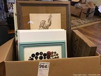 Box containing several art items including framed print, canvases, and button elephant artwork
