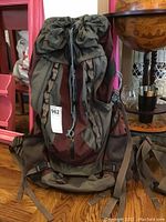 Front view of the olive green and maroon REI Venus backpack showing straps, mesh pockets and padded hip belt.