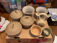 Overview of the bean pots with lids, southwestern vase and small ceramic bowls laid out on cardboard