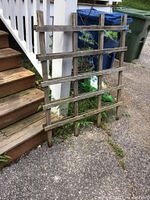 Photo of two wooden lattice panels connected at the top, leaning against stairs outdoors.