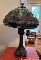 Front view of the Tiffany style lamp showing the stained glass dragonfly design on the shade and decorative metal base