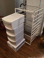 Set of 5 white plastic sliding drawer bins stacked next to the metal storage unit on wood floor