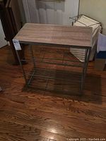 Full view of lightweight metal shelf unit with three metal wire shelves and faux wood top.