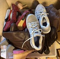 Various women's shoes piled together including boots, sneakers, heels, and flats showing multiple colors and styles.