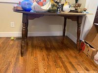 Photo of the full wooden dining table showing the top surface and legs, displaying the overall condition and size.