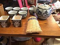 Full lot view showing teapot, cups, and wicker baskets on wooden table