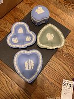 All four pieces shown together on wood flooring and black mat: blue jasperware trinket box with lid, blue heart- and club-shaped trinket dishes, green spade-shaped trinket dish
