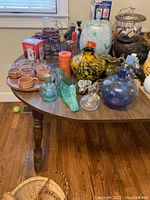 Wide shot on table showing assorted vases, glass figurines, candle, and other decorative items