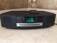 Front view of Wave system displaying FM mode, clock and preset tuning indicator with remote on top