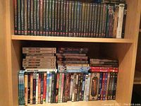 Overall view of upper two shelves showing uniform TV series spines and assorted DVDs