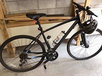 Full view of matte black hybrid bike leaning against wall