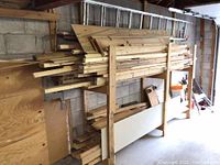 Overall view of stacked boards on wooden rack with ladder above