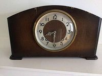 Front view of the Seth Thomas mantle clock showing wooden case and circular clock face with brass rim.