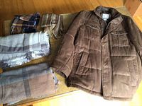 Overview of all items including brown Bugatti coat and four scarves laid on table.