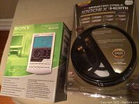Photo showing Sony RM-AV2500 central control unit box with remote picture and Monster 1000EX HDMI cable retail packaging with visible technical icons and specs.