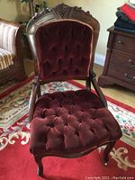Front view of the Victorian style plush chair showing tufted velvet seat and carved wood frame