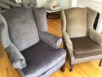 Pair of wingback chairs, one dark gray and one brown, showing full front and side angles with visible wear on fabric and cushions