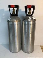 Two empty 20 lb aluminum CO2 tanks standing side by side showing overall condition and valves.