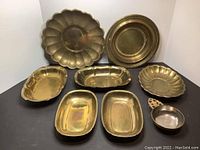 Top view of all 8 brass serving dishes and porringer arranged flat showing shapes and sizes.