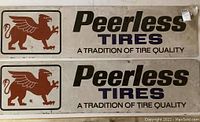 Front view of two horizontal Peerless Tires sheet metal signs with griffin logo and slogan, showing overall condition and layout.