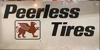 Large rectangular Peerless Tires branded sign with black text and brown griffin emblem on white background showing wear and mounted on wood frame.