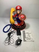 Overview of assembled Mario phone with handset, power adapter, line cord, and manual